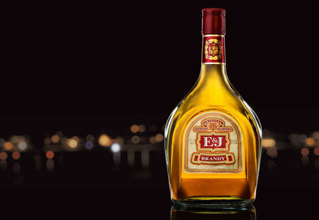 Bottle of E&J Brandy photographed in front of city nightscape